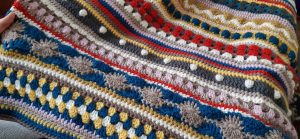 A close up view of a crochet sample blanket full of beautiful colours and patterns