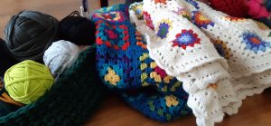 A crochet basket on the left full of yarn and crochet blankets on the right