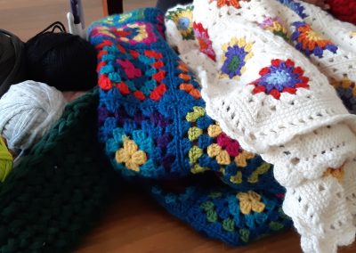A crochet basket on the left full of yarn and crochet blankets on the right