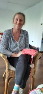 Eva smiling with her pink crochet sample sat in a chair