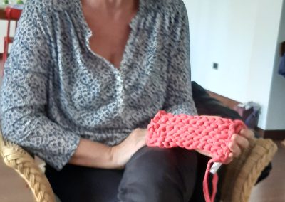 Eva smiling with her pink crochet sample sat in a chair