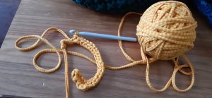 A ball of orange yarn attached to the crochet sample and crochet hook attached