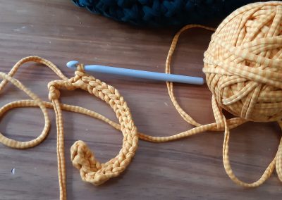 A ball of orange yarn attached to the crochet sample and crochet hook attached